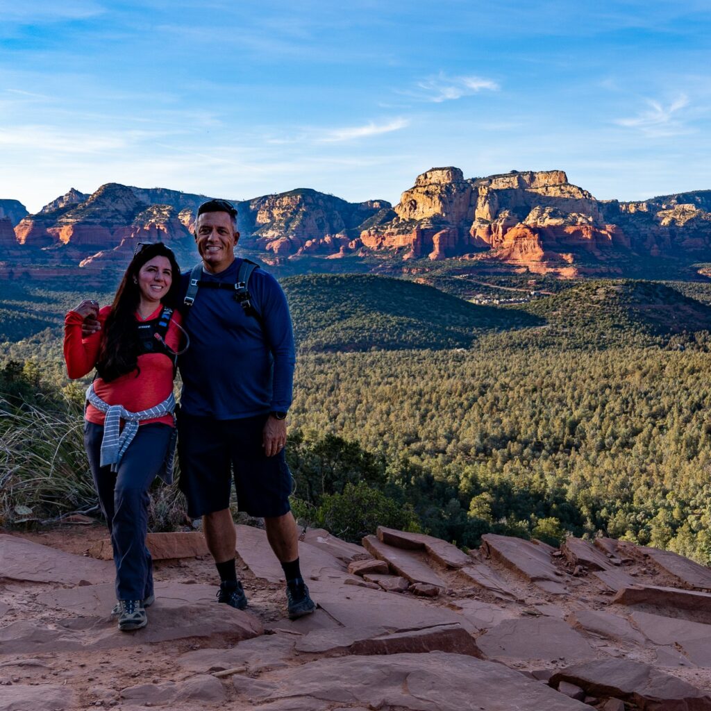 A couple hiking Devil's Bridge Trail in Sedona with rock formation in background
